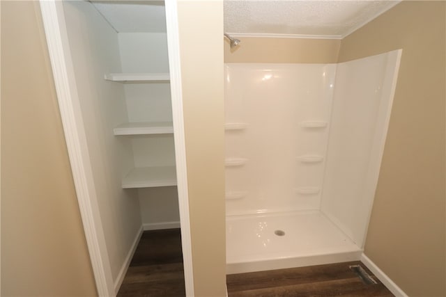 bathroom with a textured ceiling, hardwood / wood-style flooring, and walk in shower