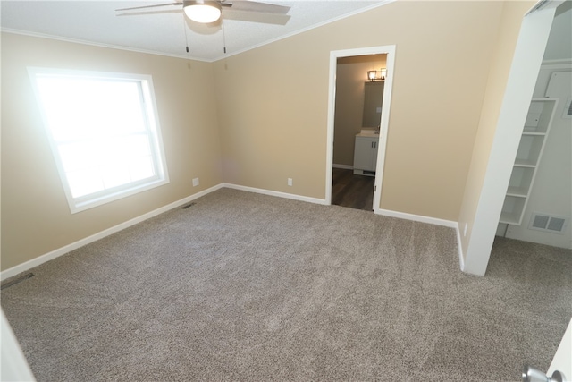 unfurnished bedroom featuring carpet, ensuite bathroom, a walk in closet, and crown molding