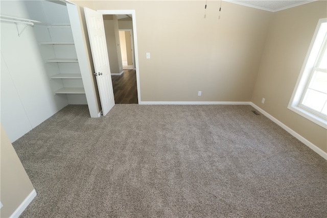 unfurnished bedroom featuring dark colored carpet and ornamental molding