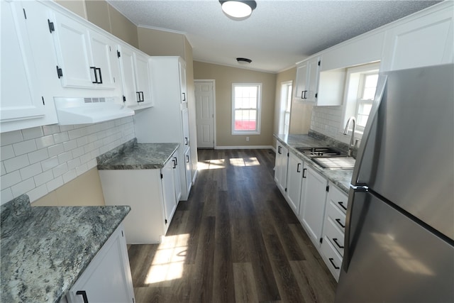 kitchen featuring dark hardwood / wood-style floors, decorative backsplash, stainless steel refrigerator, white cabinetry, and extractor fan