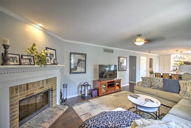 1077 Cornell Dr, Decatur, IL 62522 - living area featuring crown molding, dark wood-style flooring, a brick fireplace, and a chandelier