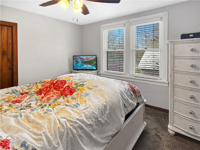bedroom with ceiling fan, dark colored carpet, and baseboards