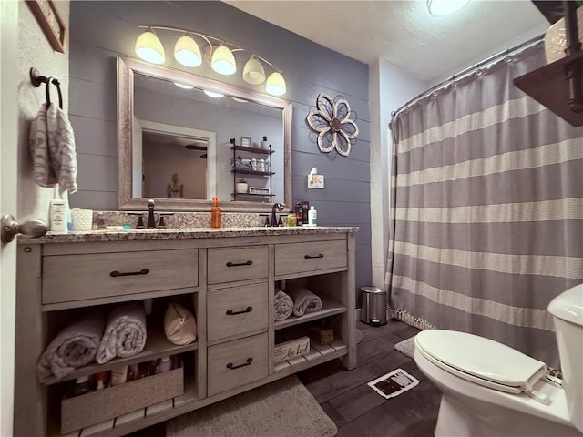 bathroom with hardwood / wood-style floors, vanity, toilet, and walk in shower