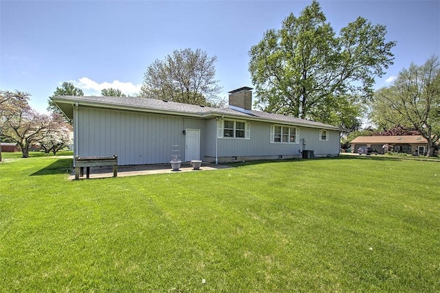 back of house with a lawn, a chimney, and central AC unit