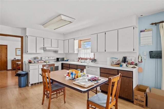 516 E Monroe Ave, Chrisman, IL 61924 - kitchen featuring white appliances, light wood-type flooring, light countertops, under cabinet range hood, and white cabinets