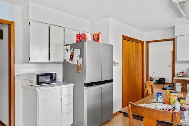516 E Monroe Ave, Chrisman, IL 61924 - kitchen with freestanding refrigerator, white cabinets, light wood-type flooring, light countertops, and baseboards
