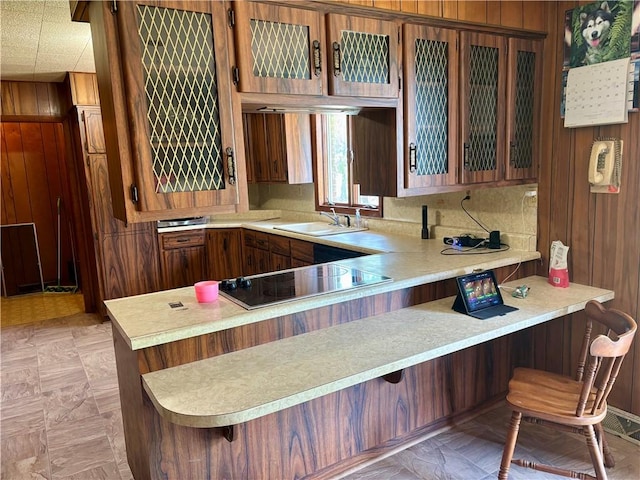 2496 N 300th St, Mason, IL 62443 - kitchen featuring wood walls, a peninsula, black electric cooktop, light countertops, and a breakfast bar