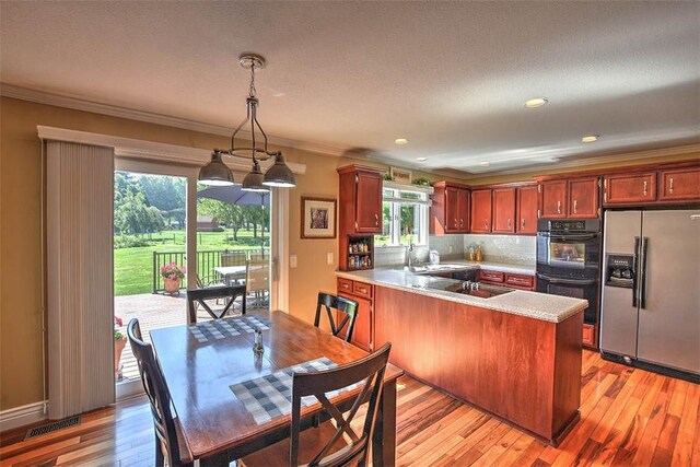 95 Hickory Point Ct, Forsyth, IL 62535 - kitchen with black appliances, ornamental molding, a peninsula, light wood-style floors, and light countertops