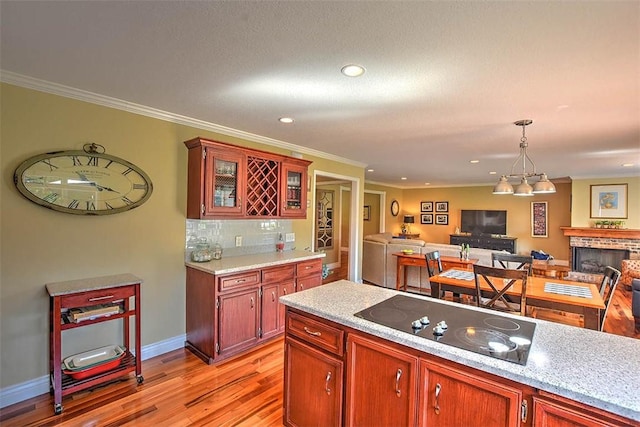 95 Hickory Point Ct, Forsyth, IL 62535 - kitchen featuring black electric stovetop, open floor plan, light wood-style floors, light countertops, and a brick fireplace