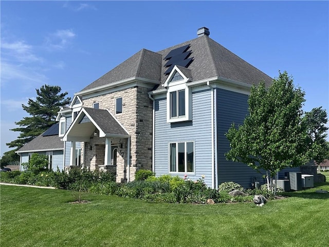 32 S Country Club Rd, Mattoon, IL 61938 - view of front of property featuring a front yard, a chimney, roof mounted solar panels, and stone siding