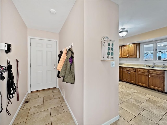 doorway to outside featuring light tile patterned floors, baseboards, and a sink