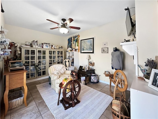 sitting room featuring tile patterned floors, baseboards, and a ceiling fan