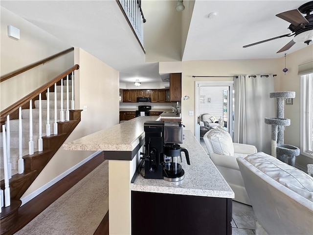 living area with stairway, baseboards, and ceiling fan