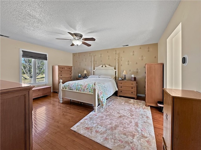 bedroom featuring wallpapered walls, light wood-style floors, visible vents, and a textured ceiling