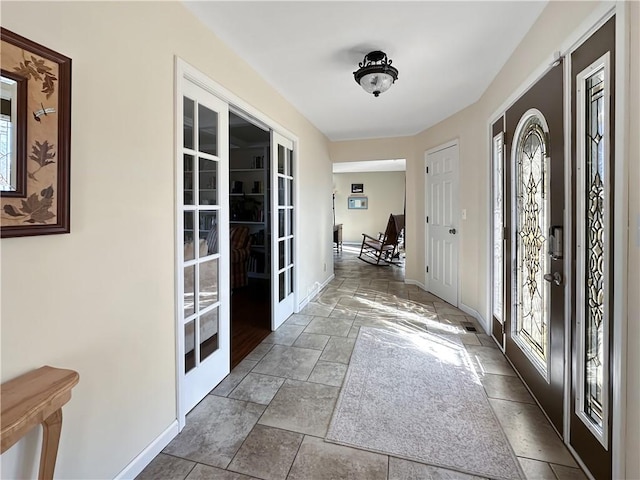 entrance foyer with stone finish floor, french doors, and baseboards