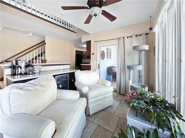 living room with stairs, beverage cooler, and ceiling fan