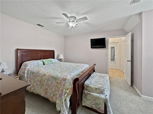 bedroom featuring visible vents, a textured ceiling, baseboards, light colored carpet, and ceiling fan