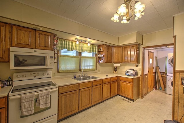 1212 Washington St, Clinton, IL 61727 - kitchen featuring white appliances, estacked washer and dryer, crown molding, brown cabinets, and light countertops