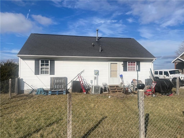 rear view of house with central AC unit and a lawn