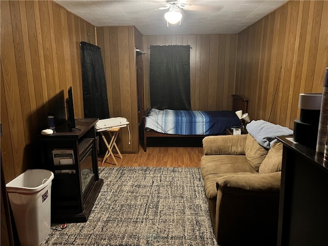 bedroom featuring ceiling fan, wood walls, and light hardwood / wood-style flooring