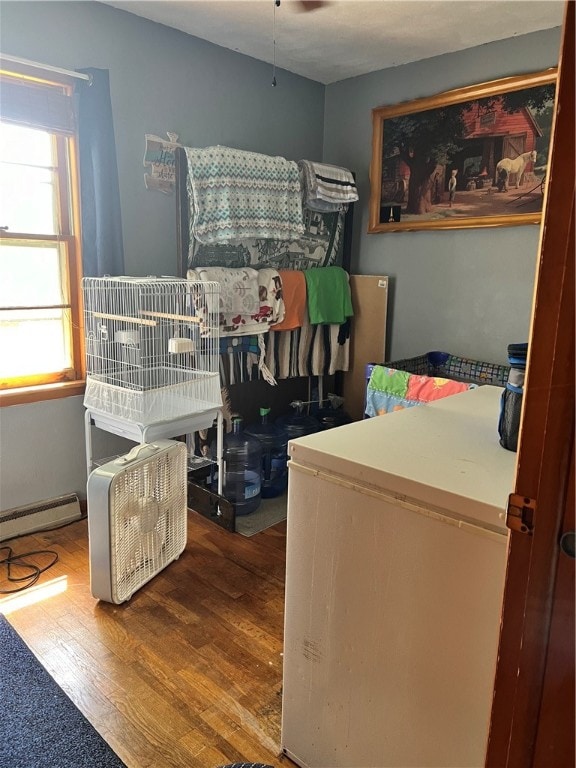 bedroom featuring hardwood / wood-style flooring and a baseboard heating unit