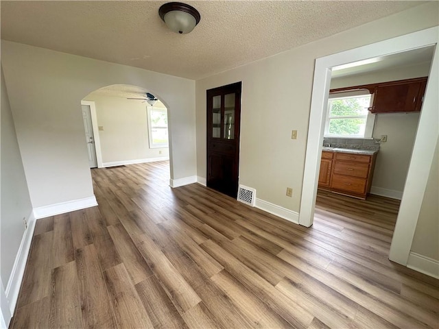 126 E Elliott St, Paris, IL 61944 - empty room featuring arched walkways, wood finished floors, a textured ceiling, and a ceiling fan