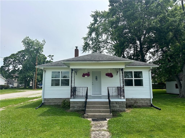 126 E Elliott St, Paris, IL 61944 - bungalow with a chimney, a porch, a front yard, and a shingled roof