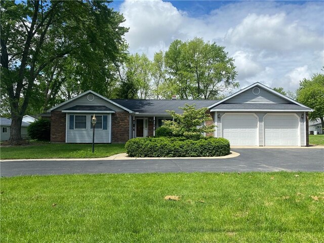 303 S Pine St, Pana, IL 62557 - single story home featuring asphalt driveway, a garage, a front lawn, and brick siding
