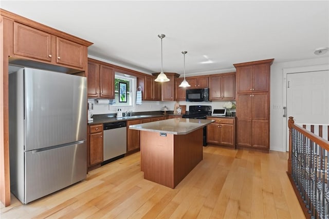 309 Santa Barbara Dr, Effingham, IL 62401 - kitchen with stainless steel appliances, light wood finished floors, a center island, hanging light fixtures, and brown cabinets