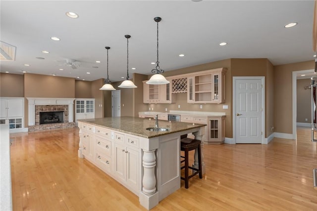 17212 Stonecreek Dr, Effingham, IL 62401 - kitchen featuring ceiling fan, an island with sink, light wood-style floors, glass insert cabinets, and recessed lighting