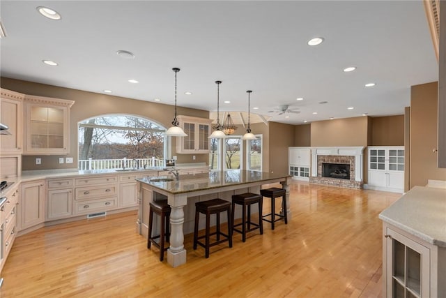 17212 Stonecreek Dr, Effingham, IL 62401 - kitchen with ceiling fan, light wood-style flooring, glass insert cabinets, a breakfast bar, and recessed lighting