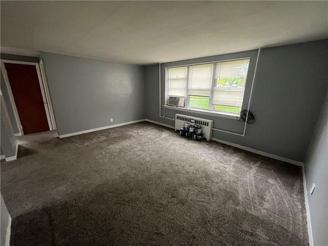 empty room featuring dark colored carpet and baseboards