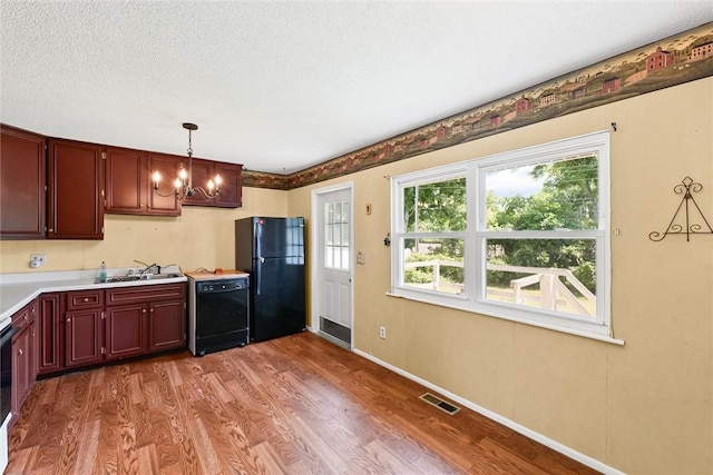 2701 E Rd, Danville, IL 61832 - kitchen featuring black appliances, wood finished floors, a chandelier, light countertops, and decorative light fixtures
