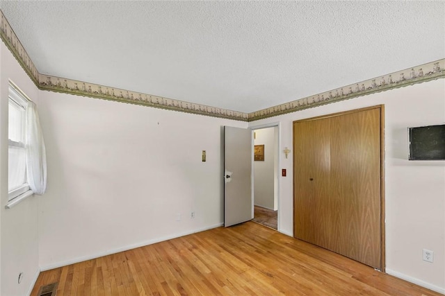 2701 E Rd, Danville, IL 61832 - unfurnished bedroom with light wood-style flooring, a textured ceiling, and a closet
