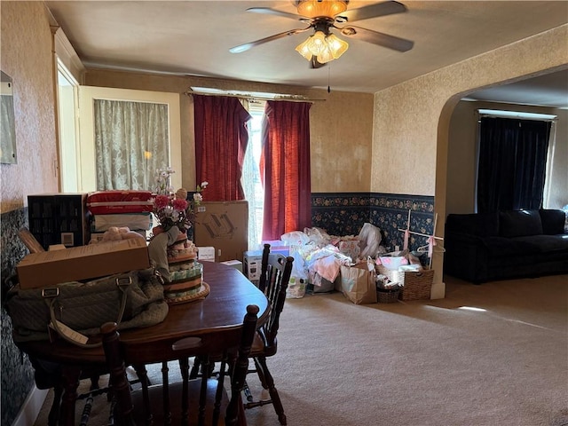 dining room with a textured wall, carpet floors, arched walkways, and ceiling fan