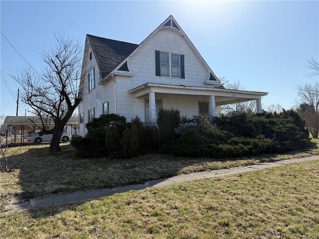 view of front of house featuring a shingled roof and a front lawn