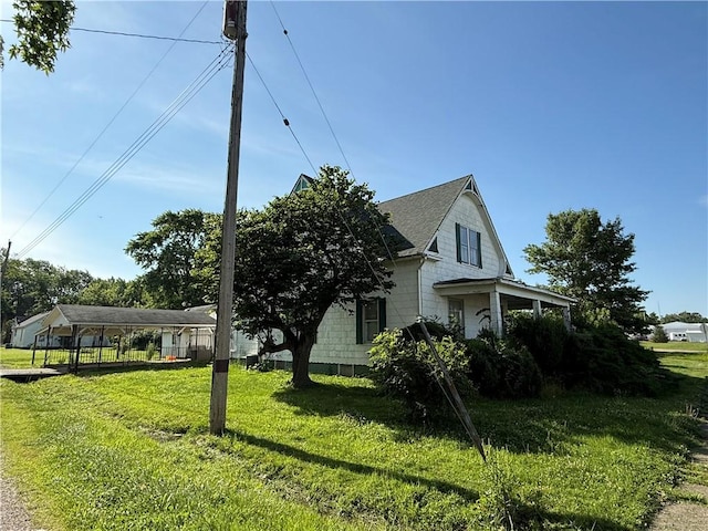 208 N Charles St, Beecher City, IL 62414 - view of property exterior with a detached carport, a lawn, and a shingled roof