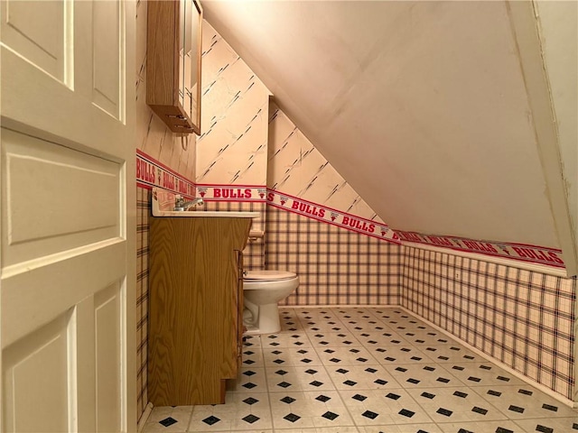 bathroom with toilet, vaulted ceiling, and wallpapered walls