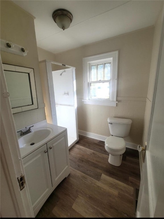 bathroom featuring a shower, vanity, hardwood / wood-style flooring, and toilet