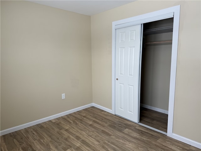 unfurnished bedroom with dark hardwood / wood-style flooring and a closet