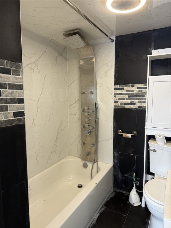 bathroom featuring toilet, tiled shower / bath combo, and tile walls