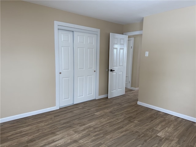 unfurnished bedroom with dark wood-type flooring and a closet