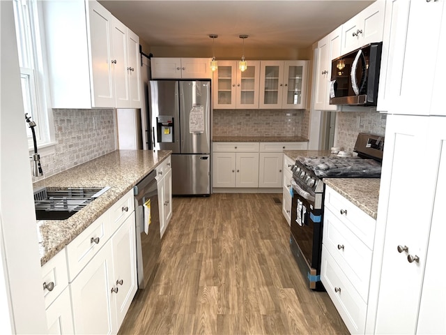 kitchen with white cabinetry, hanging light fixtures, light stone counters, stainless steel fridge with ice dispenser, and range with gas cooktop