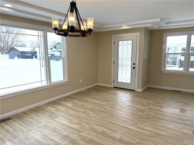 foyer featuring a notable chandelier, a tray ceiling, and wood-type flooring