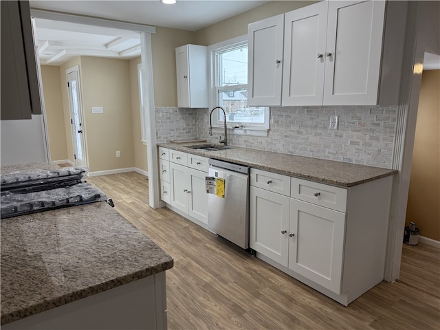 kitchen with sink, dishwasher, white cabinetry, stone countertops, and light wood-type flooring