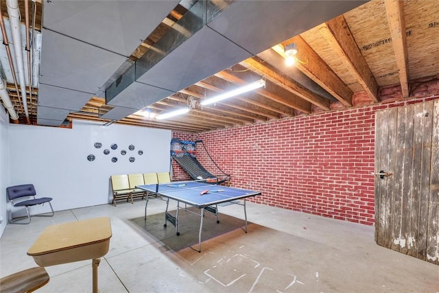 game room featuring unfinished concrete flooring and brick wall