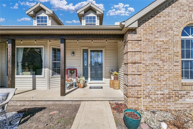 doorway to property featuring brick siding and covered porch