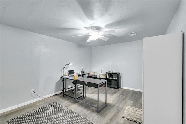 office space featuring a ceiling fan, baseboards, visible vents, and light wood-type flooring