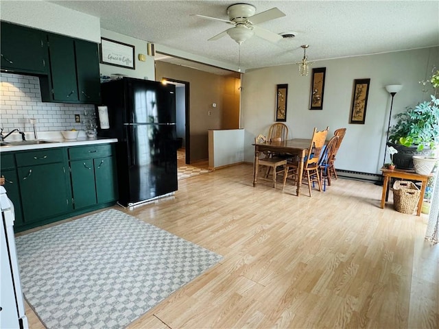 300 S Adams St, Herrick, IL 62431 - kitchen featuring freestanding refrigerator, green cabinets, a sink, light countertops, and light wood finished floors