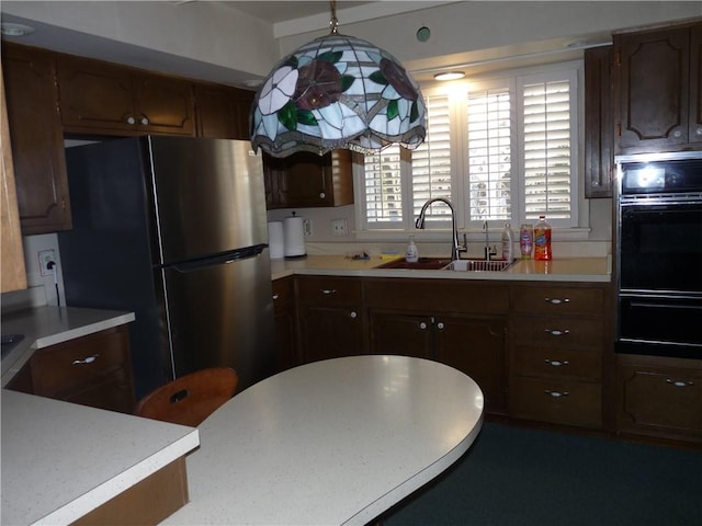 kitchen featuring pendant lighting, black double oven, stainless steel fridge, and sink